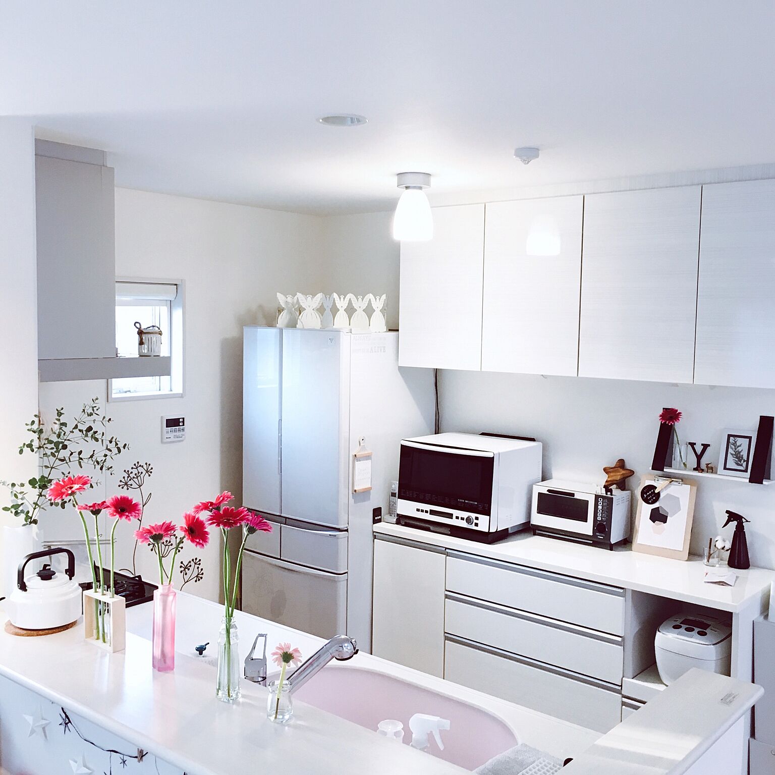 白を基調としたキッチンは清潔感があります。冷蔵庫の上のデコレーションやキッチンカウンターの上の花がかわいいですね。シンプルなだけではなくワンポイントになる飾りがあるとおしゃれです。
